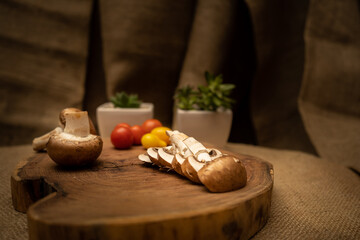 Close-up of sliced ​​portobello mushrooms on a wooden board. Burlap cloth background and fresh vegetables.