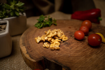 Walnuts close-up on a wooden board with various vegetables and ingredients behind.