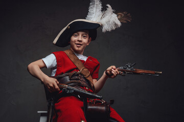 Fototapeta premium Cheerful child with handguns posing against dark background