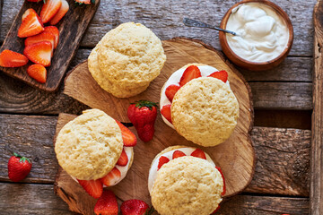Obraz na płótnie Canvas scones with strawberries and cream on a wooden background.