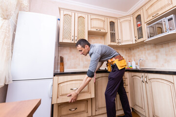 kitchen installation. Worker assembling furniture
