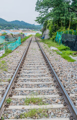 Section of railroad track in rural countryside with construction site in distance.