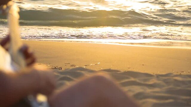 Man playing guitar by the sea at sunset