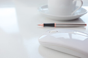 Close up of White mouse wireless, cup of coffee and pen on workdesk. 