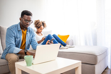 Father with kid trying to work from home during quarantine. Stay at home, work from home concept during coronavirus pandemic. Father and school-girl working form home, telework and e-learning