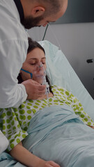 Clinical team monitoring sick woman putting oxigen mask analyzing respiratory sickness during coronavirus pandemic in hospital ward. Black nurse checking heart puls using medical oximeter