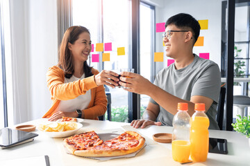 two happy officers enjoying eating pizzas chips and juice as their lunch in the office