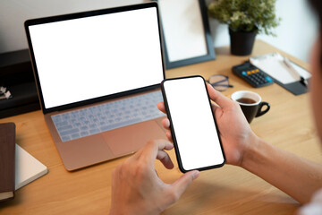 Close up view businessman sitting at office desk and using smart phone.