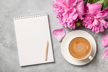 Hot coffee, peony flowers and notebook