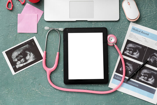 Tablet computer with stethoscope, ultrasound image of baby and accessories of obstetrician on color background