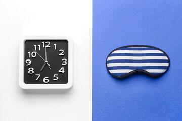 Stylish clock and sleeping mask on color background