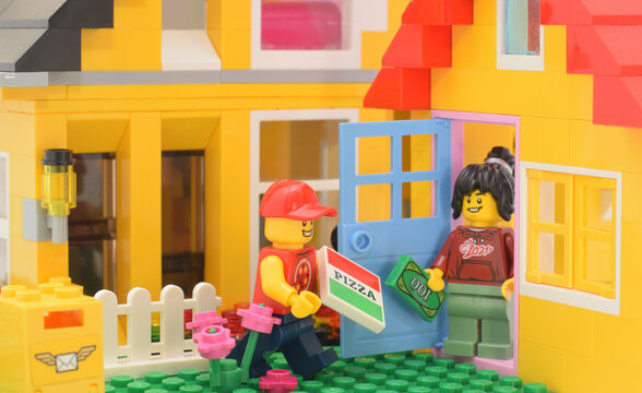 Editorial illustrative image of lego minifigure pizza deliver to home. Domestic scene with plastic toy studio shot.