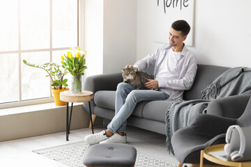 Young man with cute cat in living room
