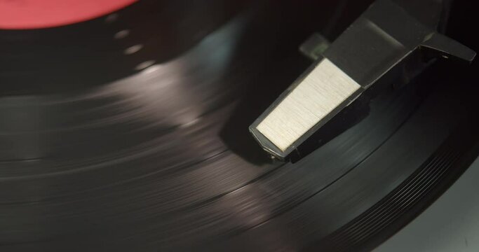 A black vinyl record is spinning on an old turntable. Analogue recording media of the 20th century.