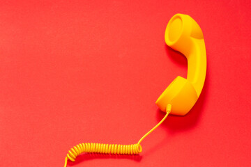 Yellow handset on red background. Copy space.