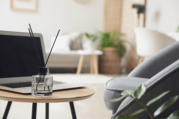Reed diffuser with laptop on table in room