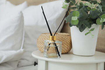 Reed diffuser with houseplant and basket on table in room