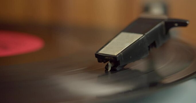 Electric vinyl record player. Close-up of a spinning vinyl record and a pickup needle. 