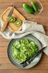 Plate with fresh salad on wooden background