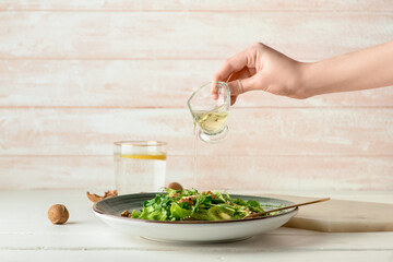 Woman cooking fresh salad on light wooden background