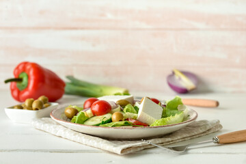 Plate with fresh salad on light wooden background