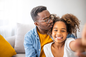 Fototapeta premium Family is the most important thing. Self portrait of young father and his little daughter smiling. Smiling father with little cute preschool daughter looking at smartphone screen taking making selfie