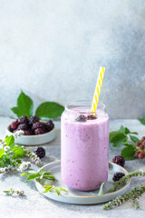Natural healthy detox, fruit dessert, healthy dieting concept. Blackberry milk shake or Yogurt smoothie in glass jar on a light stone tabletop. Copy space.