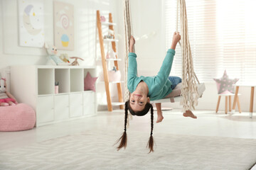 Cute little girl playing on swing at home - obrazy, fototapety, plakaty