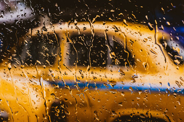 Yellow taxi behind a wet window glass