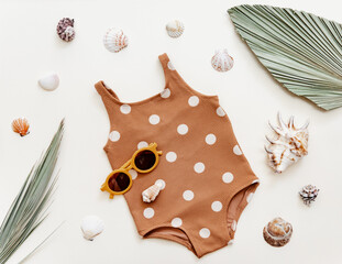 Summer kid's vacation concept - flat lay retro swimsuit with cute sunglasses on neutral background....