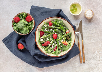 Delicious healthy salad of fresh strawberries, green asparagus, feta cheese, arugula, lettuce. Clean eating, lunch bowl.