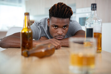man staring across table at glass of alcohol