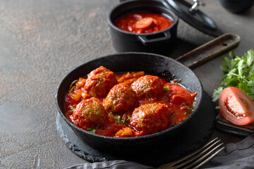 Spanish Albondigas or meatballs in with tomato sauce with ingridients on dark concrete background.Copy space