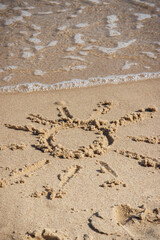 Shape of sun on sand at beach and incoming sea wave. Summer, vacation time and tourism