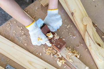 A carpenter is using a wood sharpener. Carpenter builder handles a wooden plank board plane in the workshop.