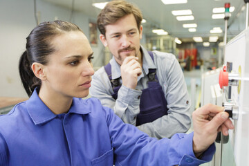 supervisor watching female worker using machinery control panel