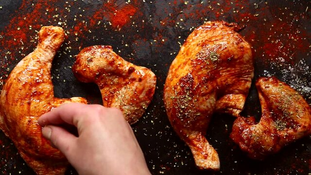Chicken thighs in spices and marinade. The cook sprinkles the chicken with spices. Raw kebab, cooking process. Top view.