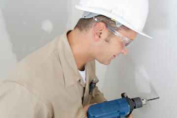man drilling the wall with drill perforator