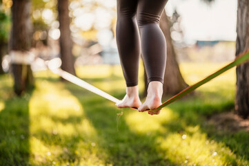 Slacklining is a practice in balance that typically uses nylon or polyester webbing. Girl walking...