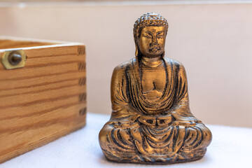 Zen golden Buddha statue sitting meditating on white background. candlelight precious stones and chest in the background.