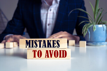 Mistakes To Avoid text concept written on wooden blocks lying on a table