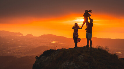 Silhouettes of parents playing with their son in a beautiful sunset on the mountain. Adventure lifestyle A summer afternoon in the mountains of the Basque country
