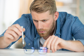 man repairing spectacles with a precision screwdriver