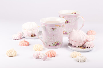 A few sweet meringues and tender marshmallows around cups with fragrant cocoa in a backlight