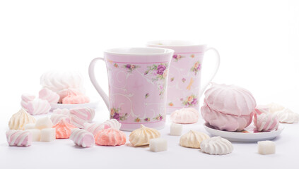 two cups of fragrant hot drink surrounded by sweets isolated on white background