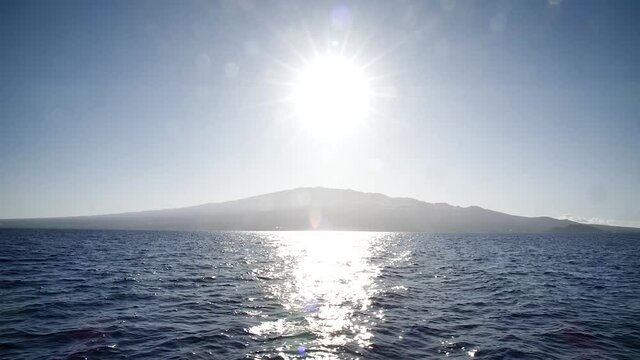Sun reflecting on the ocean with siland on the back way to Molokini Crater, Hawaii. Mid angle, static movement, slow motion, HD.