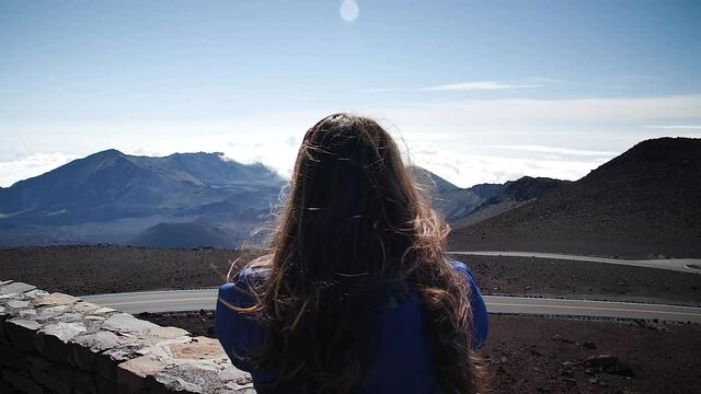 Young woman photographing clouds above the mountains in Haleakalā National Park, Maui, Hawaii. Mid angle, parallax movement, slow motion, HD.