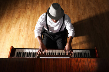 African-American man playing piano indoors, above view. Talented musician