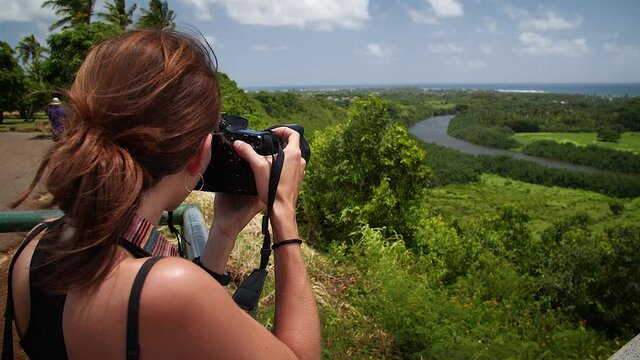 Woman photographing river and landscape from lookout in Kauai, Hawaii. Mid angle, parallax movement, slow motion, HD.
