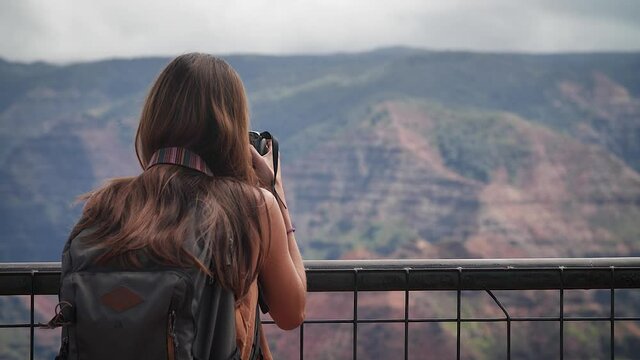Woman photographing from lookout in Waimea Canyon State Park, Kauai, Hawaii. Mid angle, parallax movement, slow motion, HD.